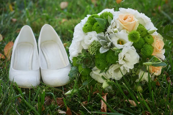 Buquê de casamento e as noivas sapatos brancos na grama — Fotografia de Stock