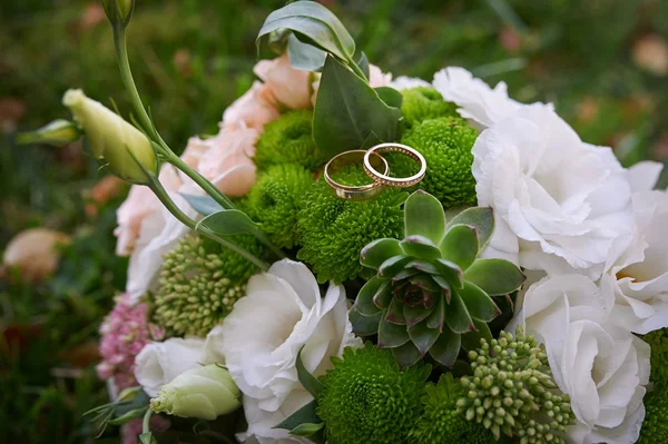 Due anelli d'oro su un bouquet da sposa spose — Foto Stock