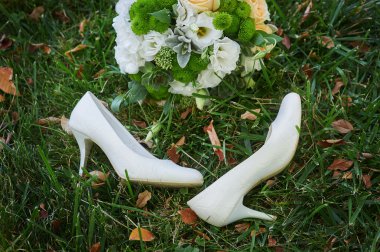 wedding bouquet and the brides white shoes on grass clipart