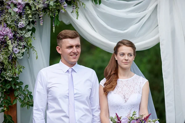 Gelin ve damat kemer altında bir düğün töreninde — Stok fotoğraf