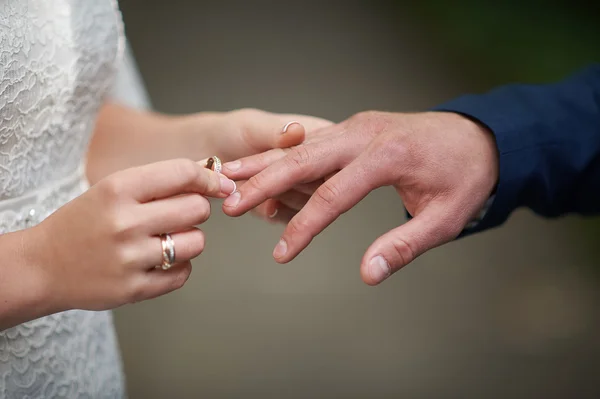 Noiva usa uma aliança de casamento no dedo do noivo — Fotografia de Stock