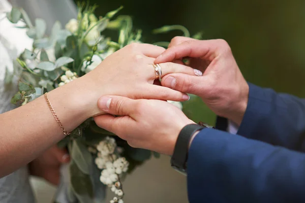 Mano del novio poniendo un anillo de bodas en el dedo de la novia —  Fotos de Stock