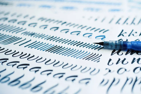 Sheet of paper with letters and brush for calligraphy — Stock Photo, Image