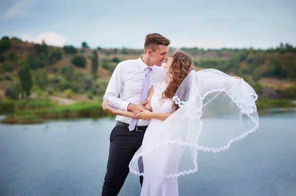 Bruid en bruidegom knuffelen op de achtergrond van de water — Stockfoto