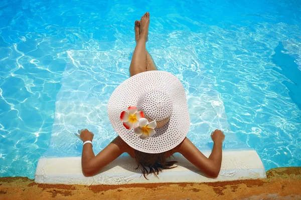 큰 백색 모자에 있는 젊은 여자는 수영장에서 안락에 휴식 — 스톡 사진