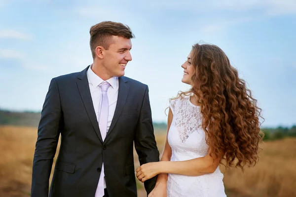 El novio y la novia caminando en el campo en el día de la boda —  Fotos de Stock