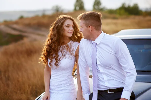 La novia y el novio se sientan en el coche en el campo en el día de la boda —  Fotos de Stock