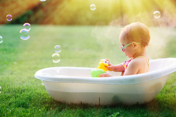 Kleines Mädchen wäscht sich im Badezimmer im grünen Gras — Stockfoto