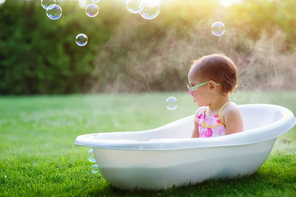 Kleines Mädchen wäscht sich im Badezimmer im grünen Gras — Stockfoto