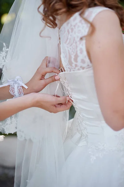 Подружка невесты помогает невесте одеваться свадебным утром — стоковое фото
