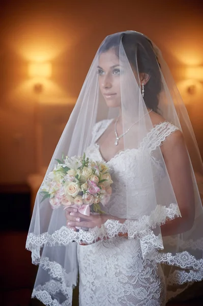 Портрет красивой невесты в свадебной вуали, держащей букет — стоковое фото