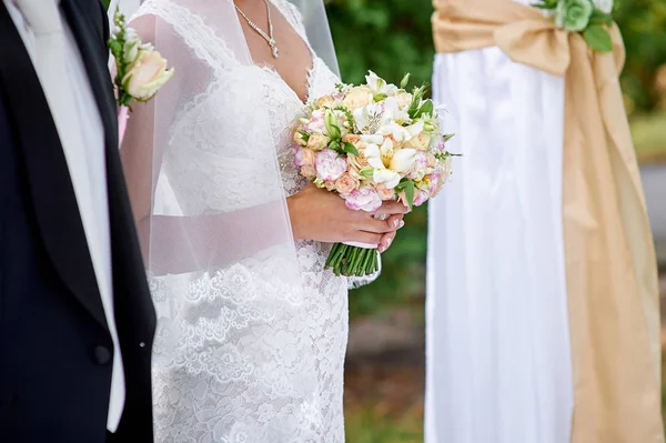 Novia y el novio de pie bajo el arco en la ceremonia de la boda — Foto de Stock