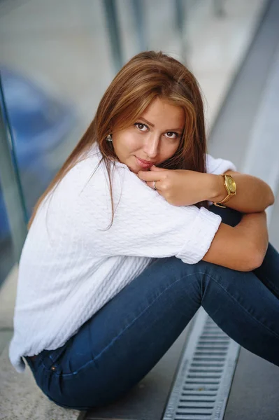 Bella giovane donna seduta vicino a un edificio di vetro — Foto Stock