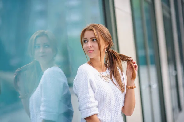 Красивая женщина стоит у большой витрины магазина — стоковое фото