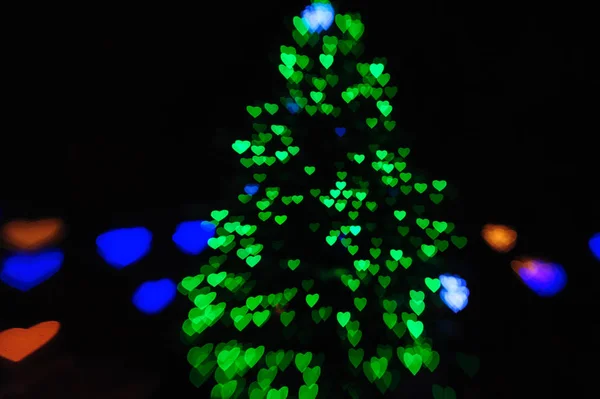 Grüne Lichter am Weihnachtsbaum in Form von verschwommenen Herzen — Stockfoto