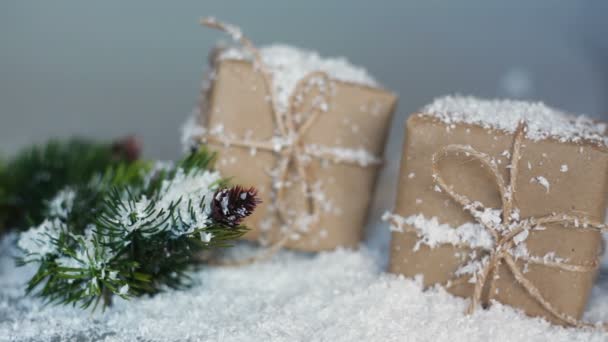 Cajas de Navidad para regalos y ramas en la nieve sobre un fondo blanco — Vídeo de stock