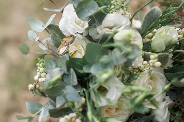 Belos anéis de casamento em um buquê de rosas brancas — Fotografia de Stock