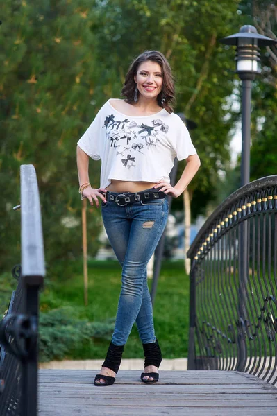 Young woman in jeans and t-shirt on a bridge — Stock Photo, Image