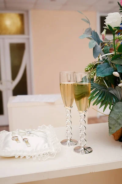 Dos copas de champán y almohada con anillos en la mesa para la ceremonia de boda — Foto de Stock