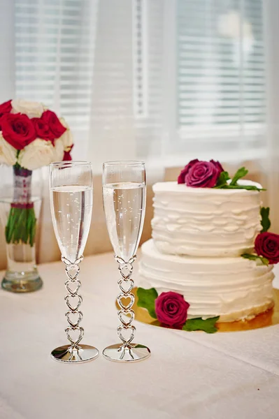 Два бокала шампанского и свадебный торт на столе — стоковое фото