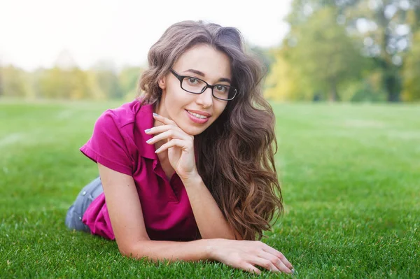 Schöne Frau liegt auf dem Gras im Park — Stockfoto