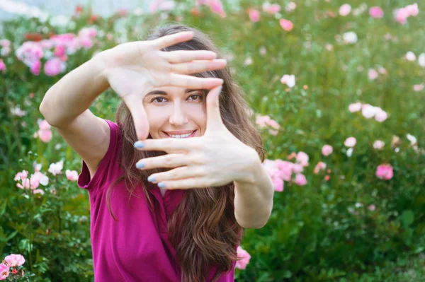 Schöne Frau blickt durch Finger in die Kamera — Stockfoto