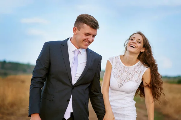 Sposa e sposo a piedi nel campo estivo — Foto Stock