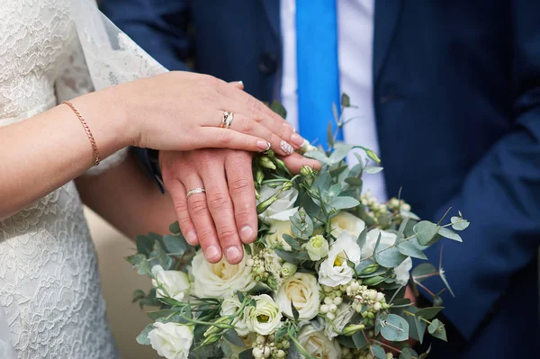 Руки жениха и невесты за свадебным букетом — стоковое фото