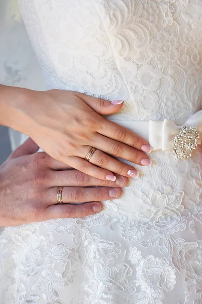 Mãos da noiva e noivo com anéis no vestido de noivas — Fotografia de Stock