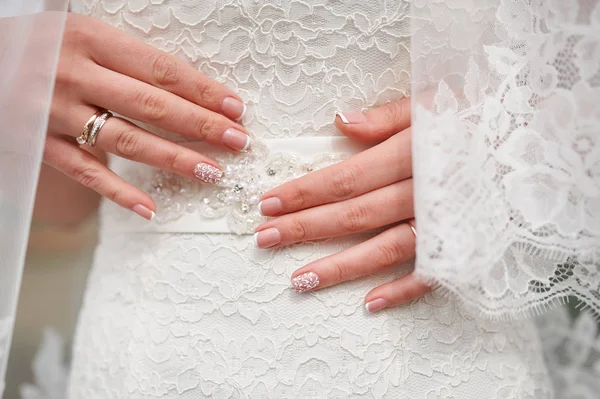 Mani di sposa con una manicure su vestito bianco, primo piano — Foto Stock