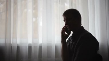 adam telefonda bir pencere yakınında arıyor