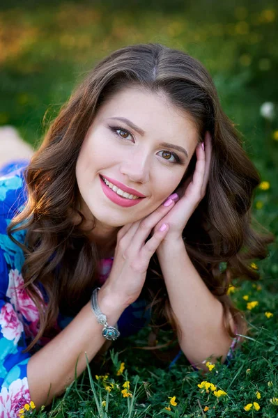 Hermosa mujer feliz acostada en la hierba con flores amarillas — Foto de Stock