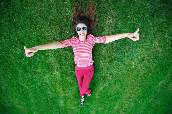 Schöne junge Frau auf dem grünen Gras auf der Wiese liegend — Stockfoto