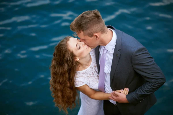 Groom kissing bride on the background of water — Stock Photo, Image