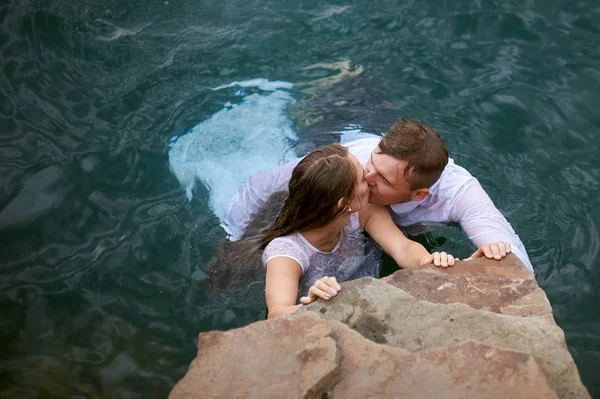 Novia y novio besándose en agua azul —  Fotos de Stock