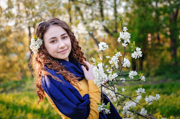 Glad ung kvinna nära ett blommande träd i parken — Stockfoto
