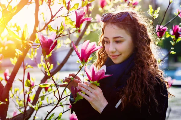 Schöne Frau, die eine Blume am Frühlingsbaum riecht — Stockfoto