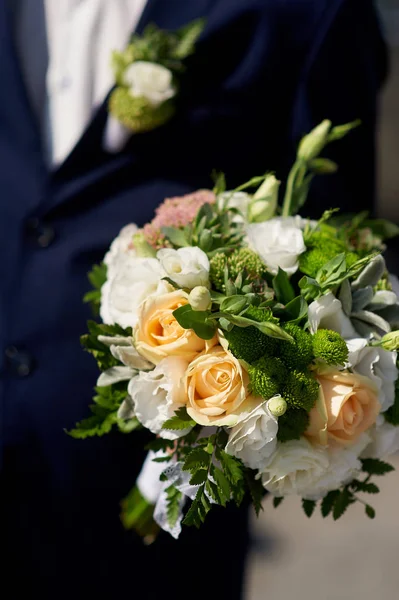 Groom holds the brides wedding bouquet — Stock Photo, Image