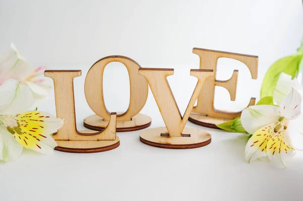 Houten letters liefde met bloemen op een witte achtergrond — Stockfoto