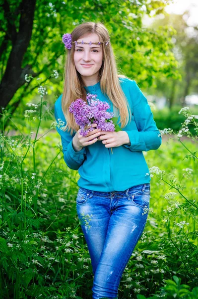 美丽的年轻女子，与一束手春天的花园里开满丁香花 — 图库照片