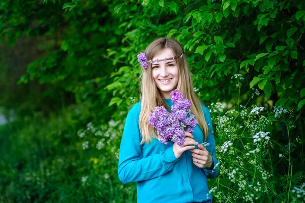 手ばねの庭のライラックの花束と美しい若い女性 — ストック写真