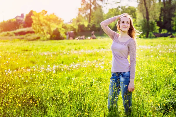 Jeune femme marchant dans une prairie avec des fleurs sauvages jaunes — Photo