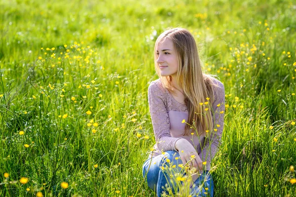 Ung kvinna promenader i en äng med gula blommor — Stockfoto