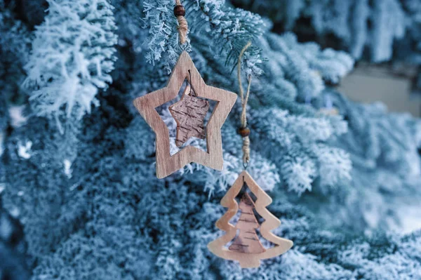 Weihnachtsspielzeug aus Holz auf einer schönen schneebedeckten Tanne im Winter — Stockfoto