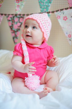 pembe elbiseli küçük kız yatakta oturur