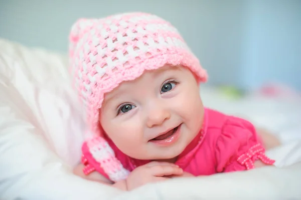 Kleines Mädchen mit Strickmütze auf dem Bett liegend — Stockfoto