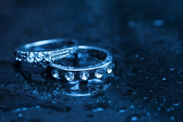 Two white gold rings on wet table — Stock Photo, Image