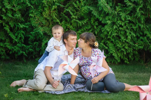 Junge Familie sitzt auf Rasen im Sommerpark — Stockfoto