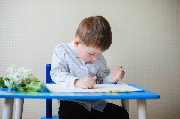 Little boy sitting at the desk draws — Stock Photo, Image