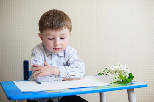 Little boy sitting at a desk and listening to the teacher — Stock Photo, Image